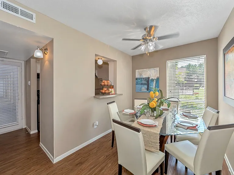 Bright dining area with large window, modern lighting, and convenient pass-through bar to the kitchen at Watersong Villas Apartments.