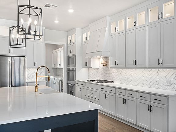The kitchen has gorgeous white wood cabinetry with a tile backsplash.