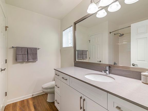 Renovated Package II bath with white cabinetry, grey quartz countertop, and hard surface flooring