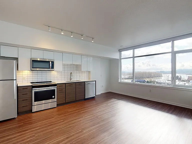 Apartment Kitchen with Stainless Steel Appliances, Dining and Living Room with Wood-Style Flooring.