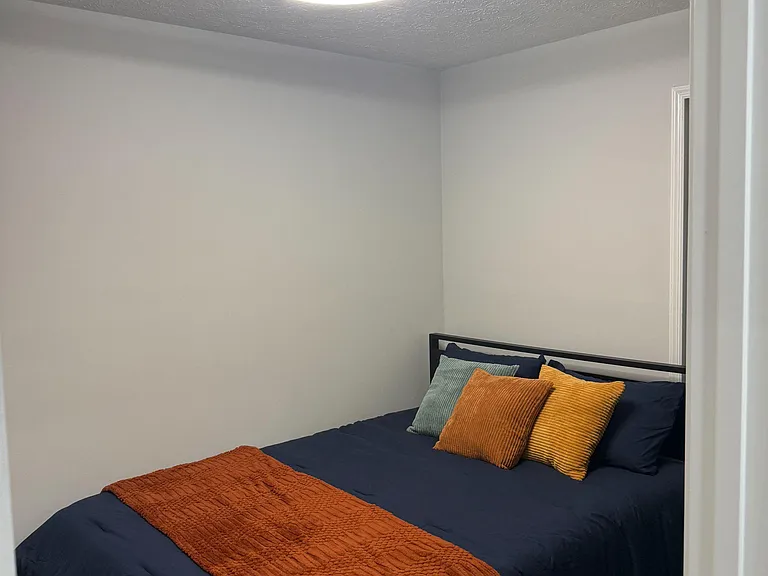 Furnished bedroom with a comfortable bed, neutral walls, and an overhead light fixture for easy everyday living.