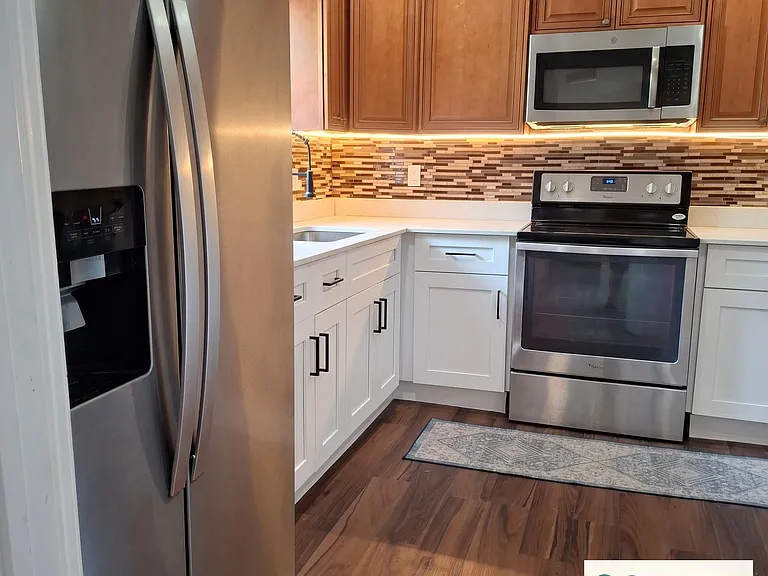 Updated kitchen featuring stainless steel appliances, shaker cabinetry, and ample counter space with a tile backsplash.