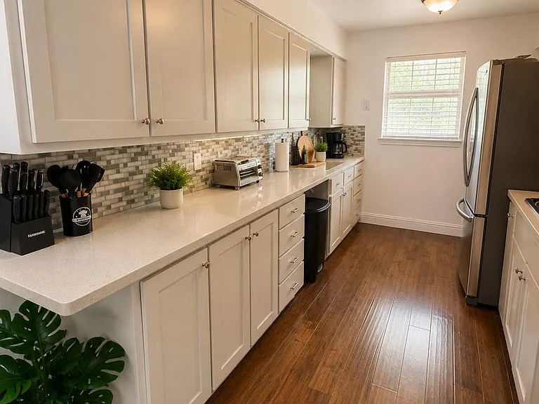 Streamlined galley kitchen with ample cabinet storage, long prep counters, and a full-size stainless refrigerator.