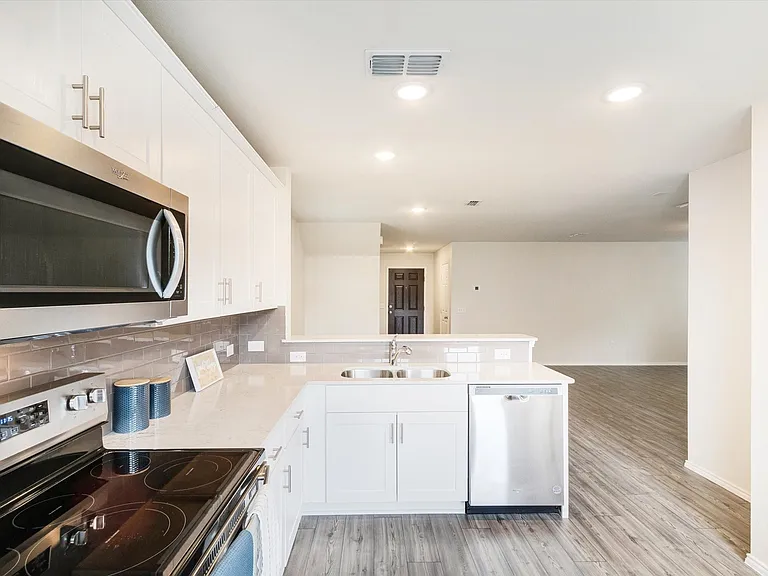 Modern kitchen featuring white cabinetry, stainless steel appliances, light-toned countertops, and a subway tile backsplash