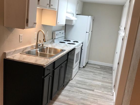 Galley kitchen with new weathered wood look tile floors, base cabinets, countertp, sink and faucet