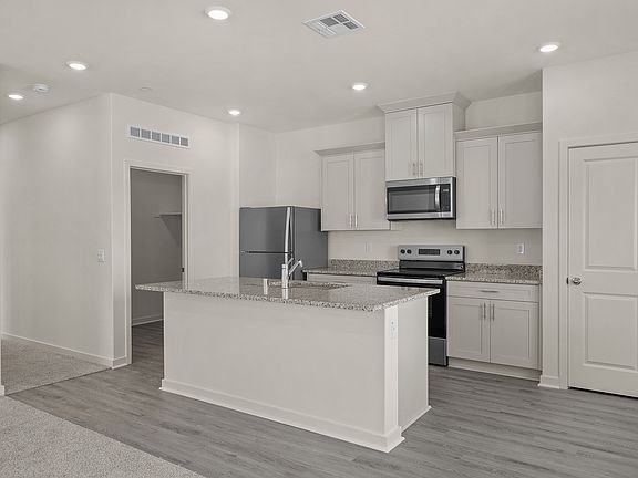 The kitchen has stainless steel appliances and plank flooring.
