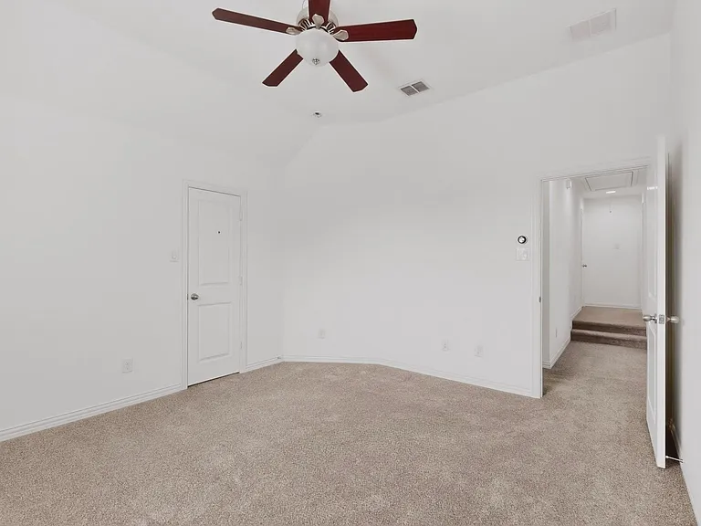 A bright bedroom featuring a ceiling fan and a walk-in closet