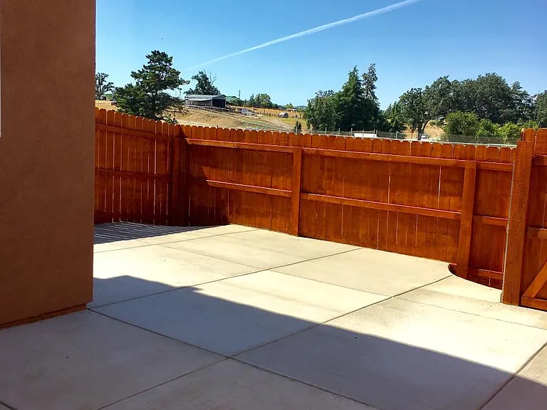 Large fenced patio has been updated with plants and stained concrete.