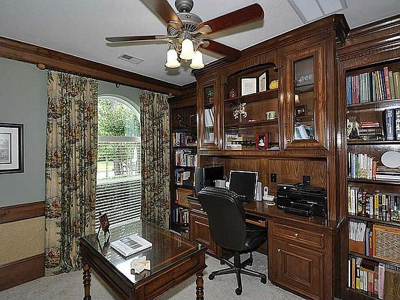 French door entrance to study with nice work area, built-in desk, rows & rows of bookshelves, storage closet & a ceiling fan.