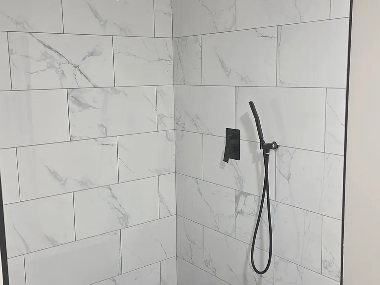 Primary shower renovations in progress with marble tile and black fixtures