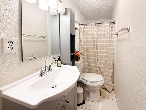 Functional full bath with a vanity sink, mirrored medicine cabinet, towel bars, and a shower/tub combo with curtain.