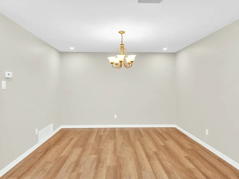 Large dining room with a chandelier, room for a large table for 8, chairs, buffet or china cabinet.
