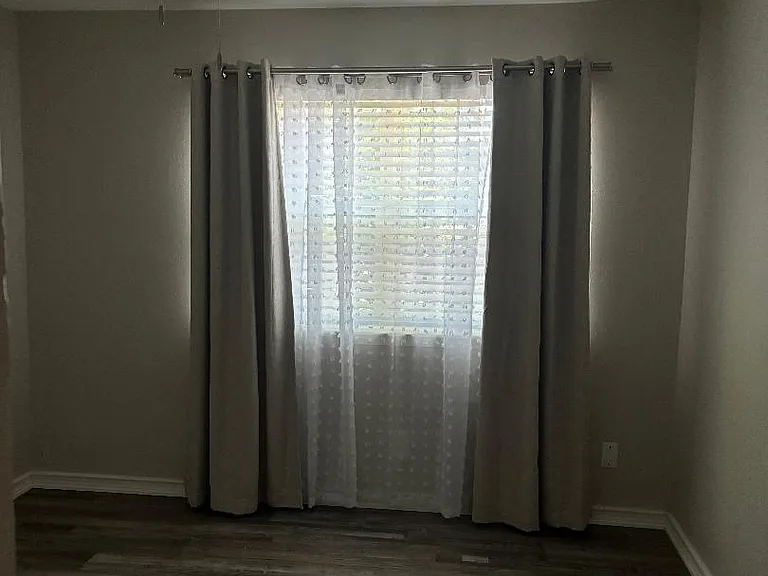First bedroom for hallway with curtains/sheers and blinds.
