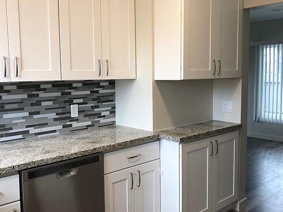 Spacious kitchen with tile backsplash. Walk into living room area.