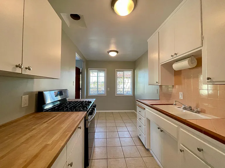 Kitchen looking east to the dining space. Newer gas range, fridge, butcher block and tile counters.