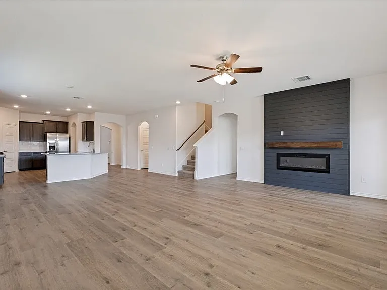 Spacious living area featuring wood-finish flooring, a contemporary fireplace with a shiplap accent wall, and recessed lighting