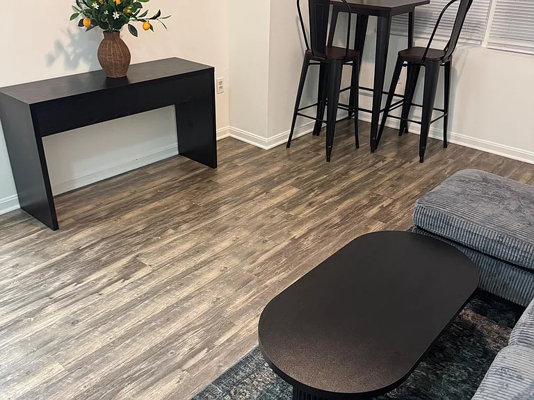 Dining nook with a bistro-height table for two, set beside a window and complemented by easy-care flooring.