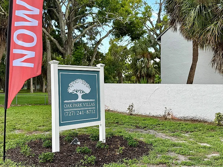Charming Oak Park Villas sign amidst lush greenery, inviting you to explore tranquil living.