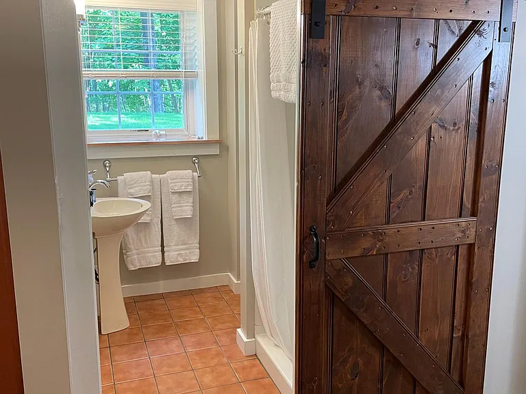 Bathroom has stand up shower, towels, mats, shower curtain.