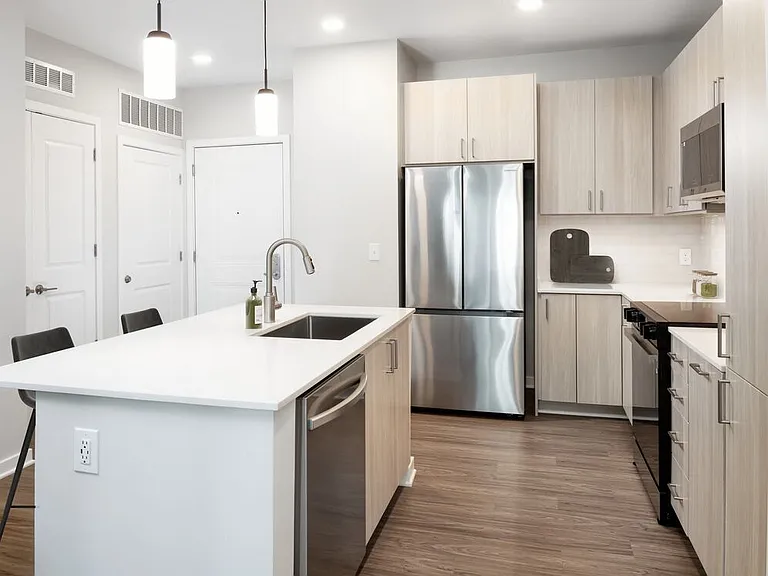 Design Collection II kitchen with stainless steel appliances, cream quartz countertops, oak cabinetry, and hard surface flooring