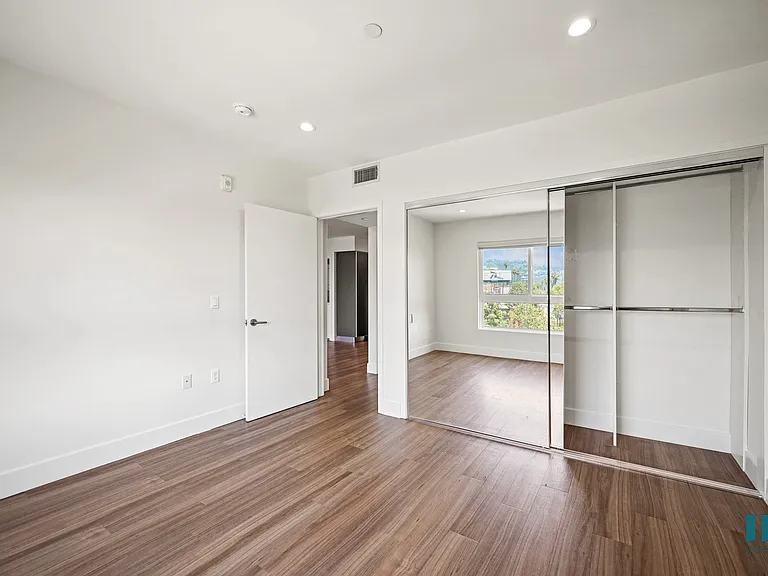 Bedroom with Vinyl Flooring, Recessed Lighting, and Mirrored Closet