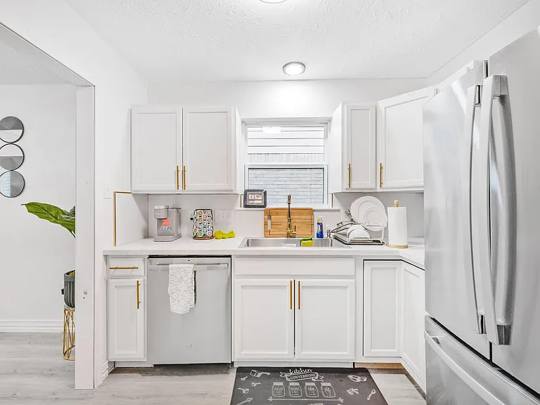 Efficient kitchen with ample white cabinetry, generous counter space, and stainless steel appliances including a dishwasher.