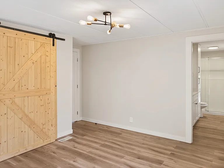 Primary Bedroom with Sliding Barn Door, Sputnik Light Fixture, and En-Suite Bathroom