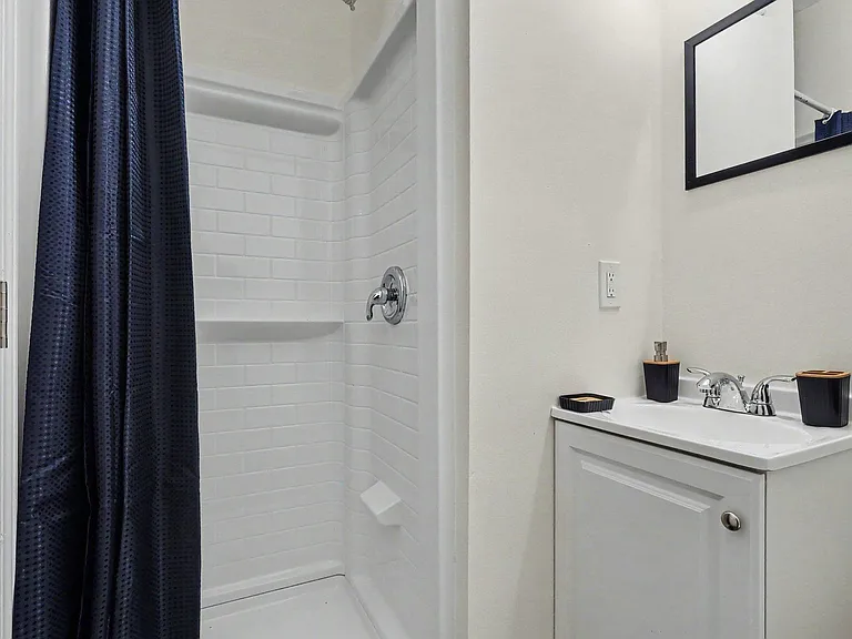 Full bathroom with a tub/shower combo, tiled surround, and vanity with mirror for convenient daily routines.