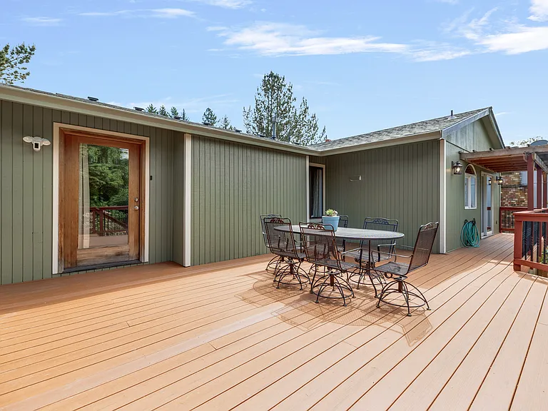Outside
+Access from kitchen/living room
+Greenhouse (lower right) 
+Dining for 6
+24*20' 
+Trex decking 
+Outdoor lighting 
+1 Ring floodlight camera upstairs by 3rd bdrm door
+2nd Ring floodlight camera located lower level (to the left of the hose)