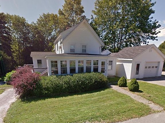 View of house with screened/glassed porch visible across the front, deck visible on the left, and garage.