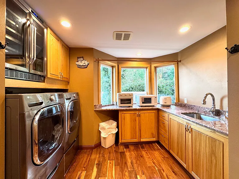 Smart Utility Room for Comfortable Family Living Spacious laundry and prep area with LG washer/dryer, wine cooler, and full kitchenette setup. Granite counters, natural light, and small appliances make everyday routines easy for families on longer stays.
