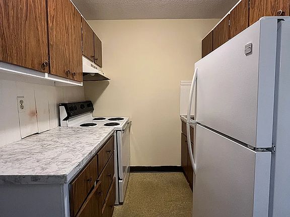 Separate galley kitchen with fridge and stove.