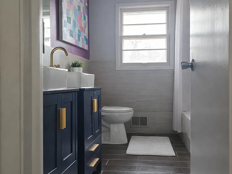 Second bathroom with bathtub, double sinks, and large linen closet.
