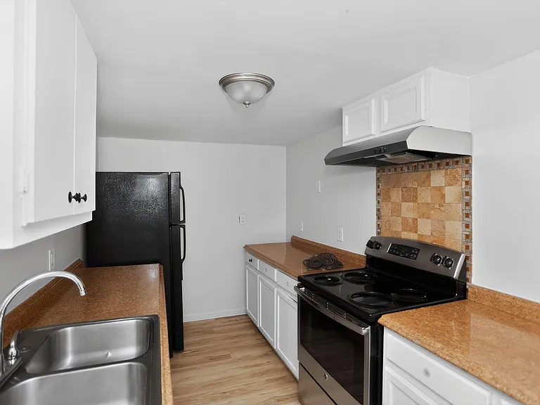 Efficient kitchen with generous counter space, ample cabinetry, a double-basin sink, and full-size range and refrigerator.
