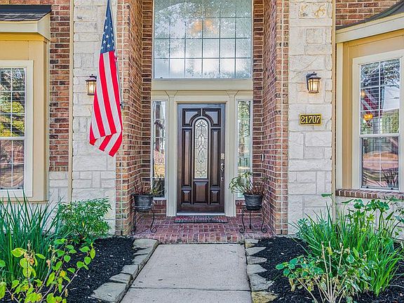 A gorgeous brick and stone elevation surrounded by pretty foliage beckons you to enter this charming home!