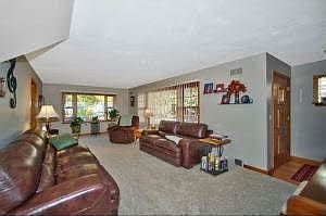 Living room w/ hardwood under carpet and guest closet in foyer