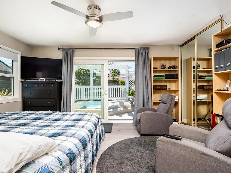 Large bedroom has ceiling fan large patio doors.