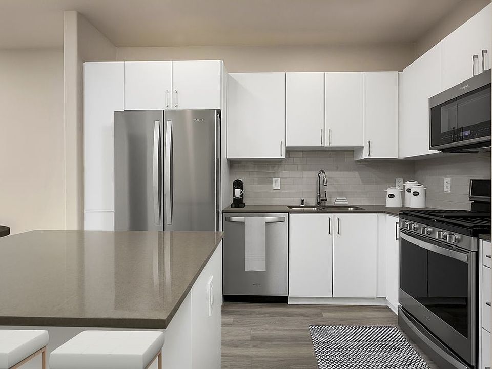 Renovated Package I kitchen with quartz countertops, white cabinetry, stainless steel appliances, hard surface vinyl plank flooring, and tile backsplash