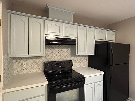 Newly painted kitchen cabinets with stove and fridge. Quartz countertops with tiled backsplash