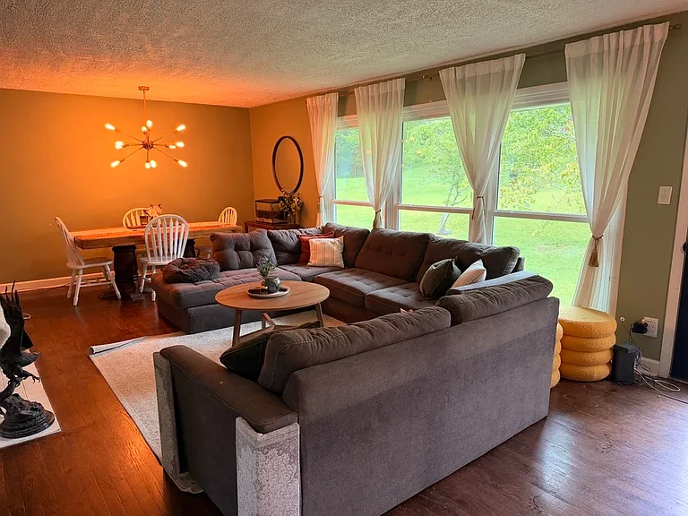Sage green living room and floor-to-ceiling windows create a bright space that invites you to settle down with a book by the gas fire or to look out at the beautiful summer storms.