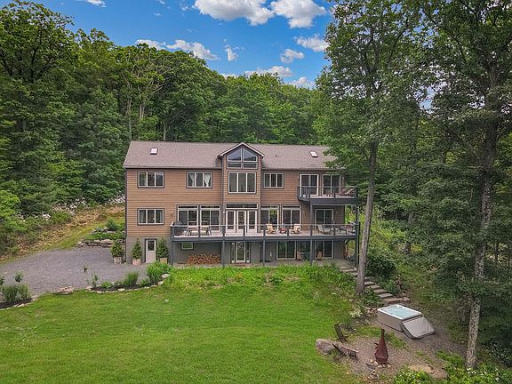 Front of house showing the deck facing the view, the parking, hot tub, fire pit, etc.