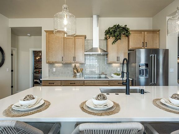 Modern kitchen with light wood cabinets, stainless steel appliances, a large island with white count