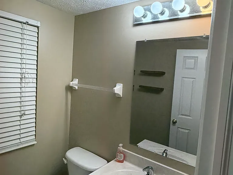 Main level half bath with single vanity and mirror.