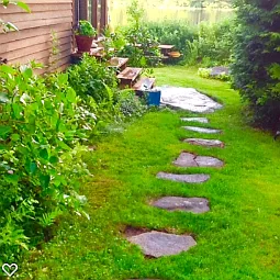 Path around side of house with steps going into the porch.
Picnic table by bushes.