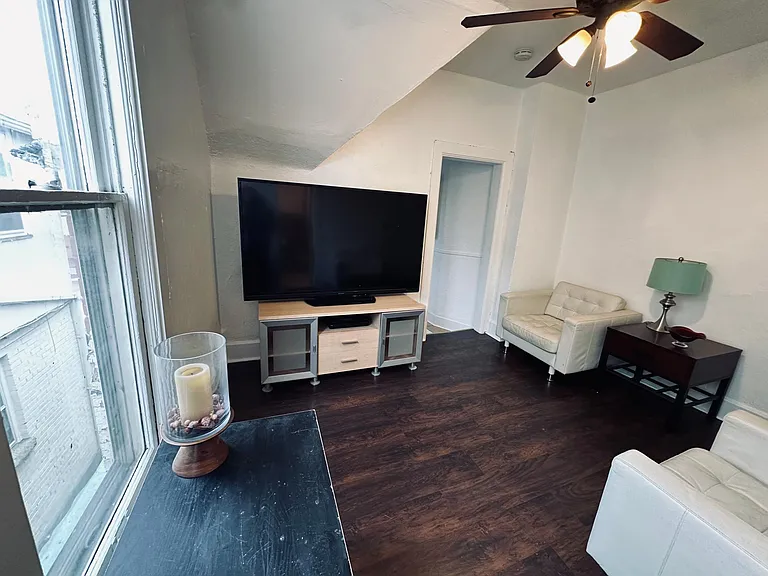 Living room view. Kitchen door on the right. Laminate wood floors.
North facing window