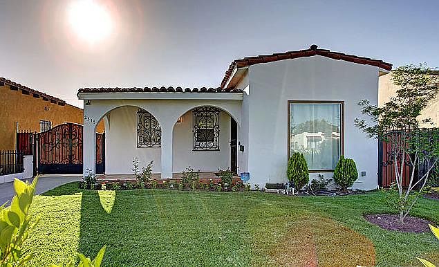 Spacious and manicured front lawn with gated entry to long driveway