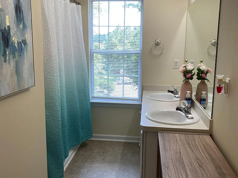 Full bathroom with a tub/shower combo, wide vanity and mirror, and a large window for natural light and ventilation.