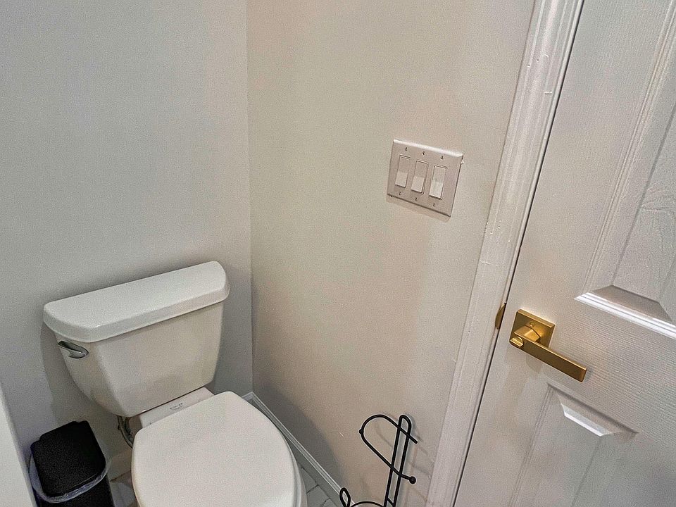Half bath with toilet, durable tile flooring, and convenient wall switches by the door for easy access.