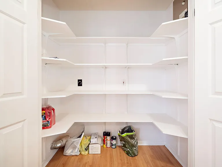 Walk-in storage closet with built-in shelving, offering ample space to organize pantry items, cleaning supplies, or luggage.