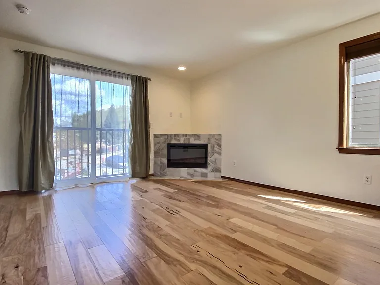 2nd Floor _ Open-concept living area featuring sleek hardwood flooring, a cozy tiled fireplace, a kitchen with stainless steel appliances and a premium slide-in electric range, plus a convenient half bathroom.